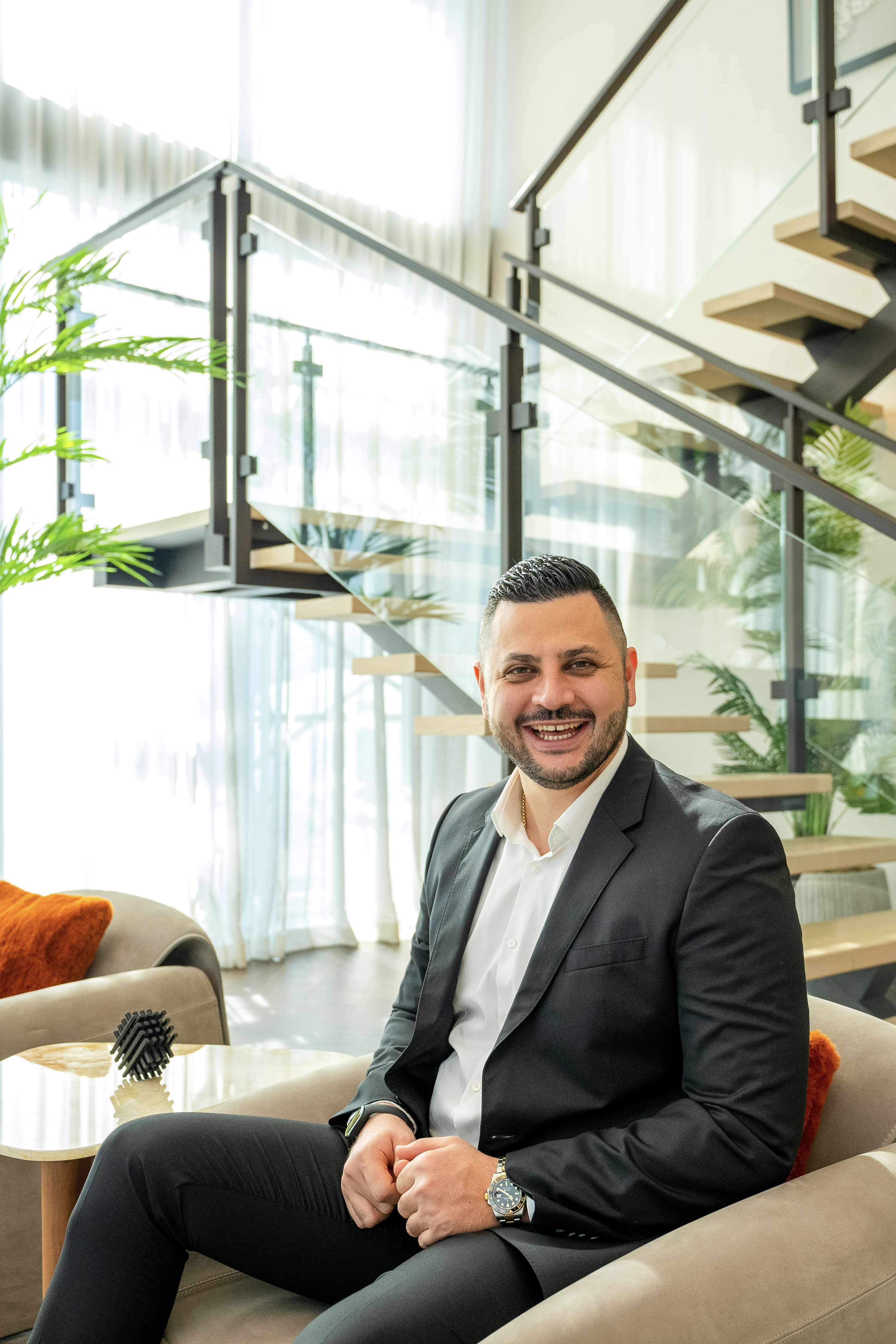 Tarlan Musaev smiling, seated in a bright lounge in a dark suit and open white shirt